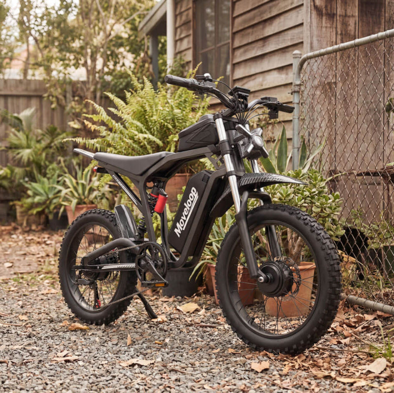 Black electric bike with 'Mensano' branding parked outdoors on a gravel surface. Moveloop T1 Ultra Electric Bike for Adults 3000W Peak Motor 48V 20AH 35 MPH 40-80 Miles All Terrain Fat Tire Electric Mountain Bike
