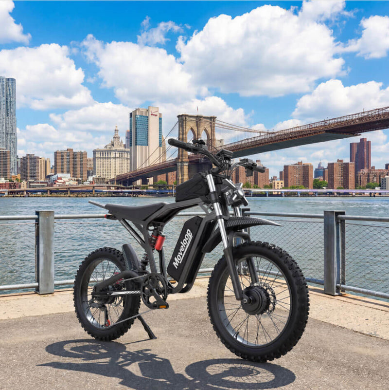Electric bike on a dock with a city skyline and bridge in the background Moveloop T1 Ultra Electric Bike for Adults 3000W Peak Motor 48V 20AH 35 MPH 40-80 Miles All Terrain Fat Tire Electric Mountain Bike
